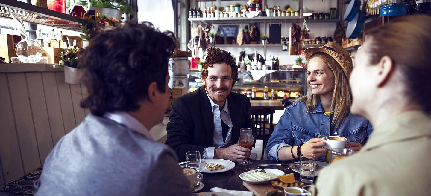Vier Personen sitzen an einem Tisch im Restaurant und lachen