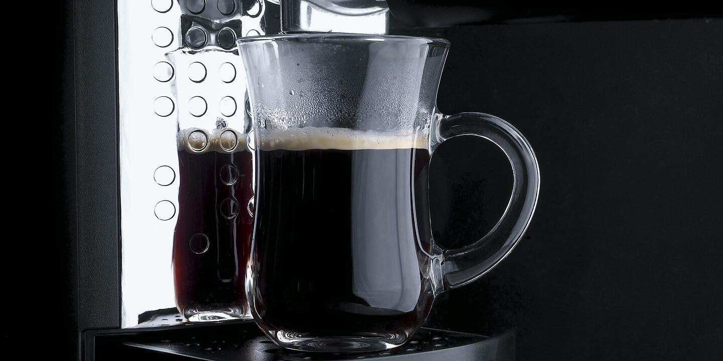 Una taza transparente llena de café de una cafetera