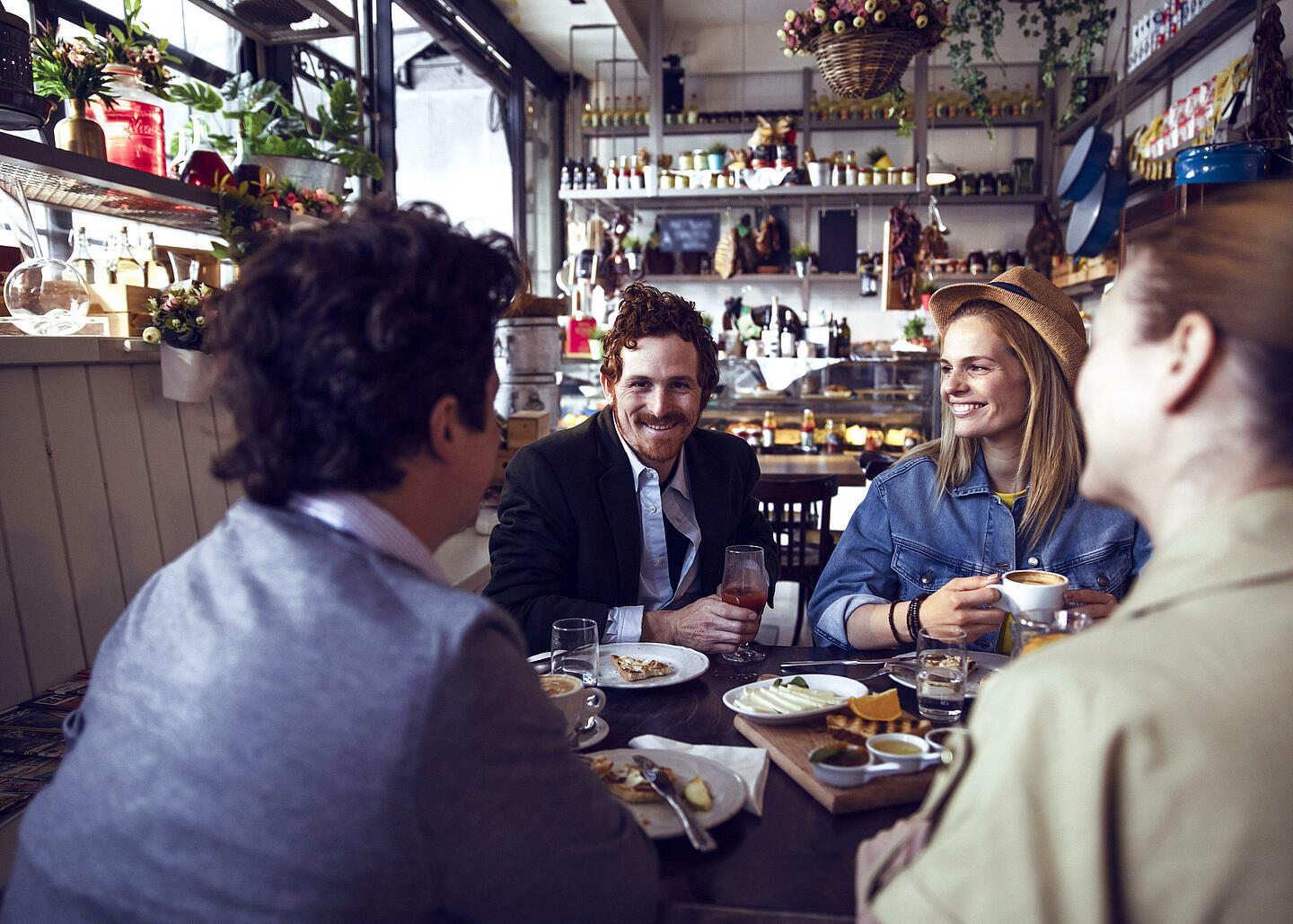 Quatre personnes assises à une table de restaurant en train de rire