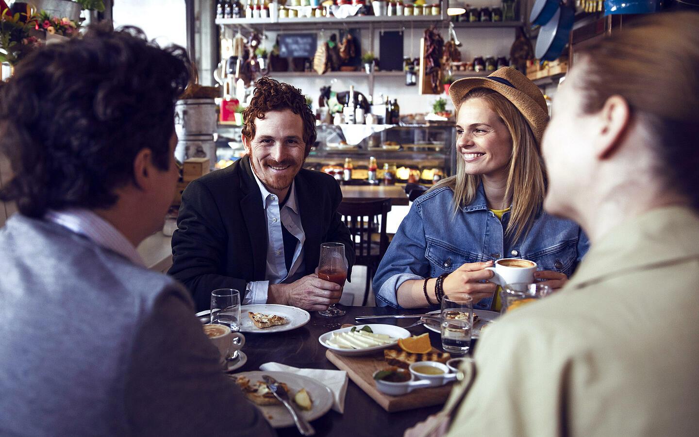 Vier Personen sitzen an einem Tisch im Restaurant und lachen