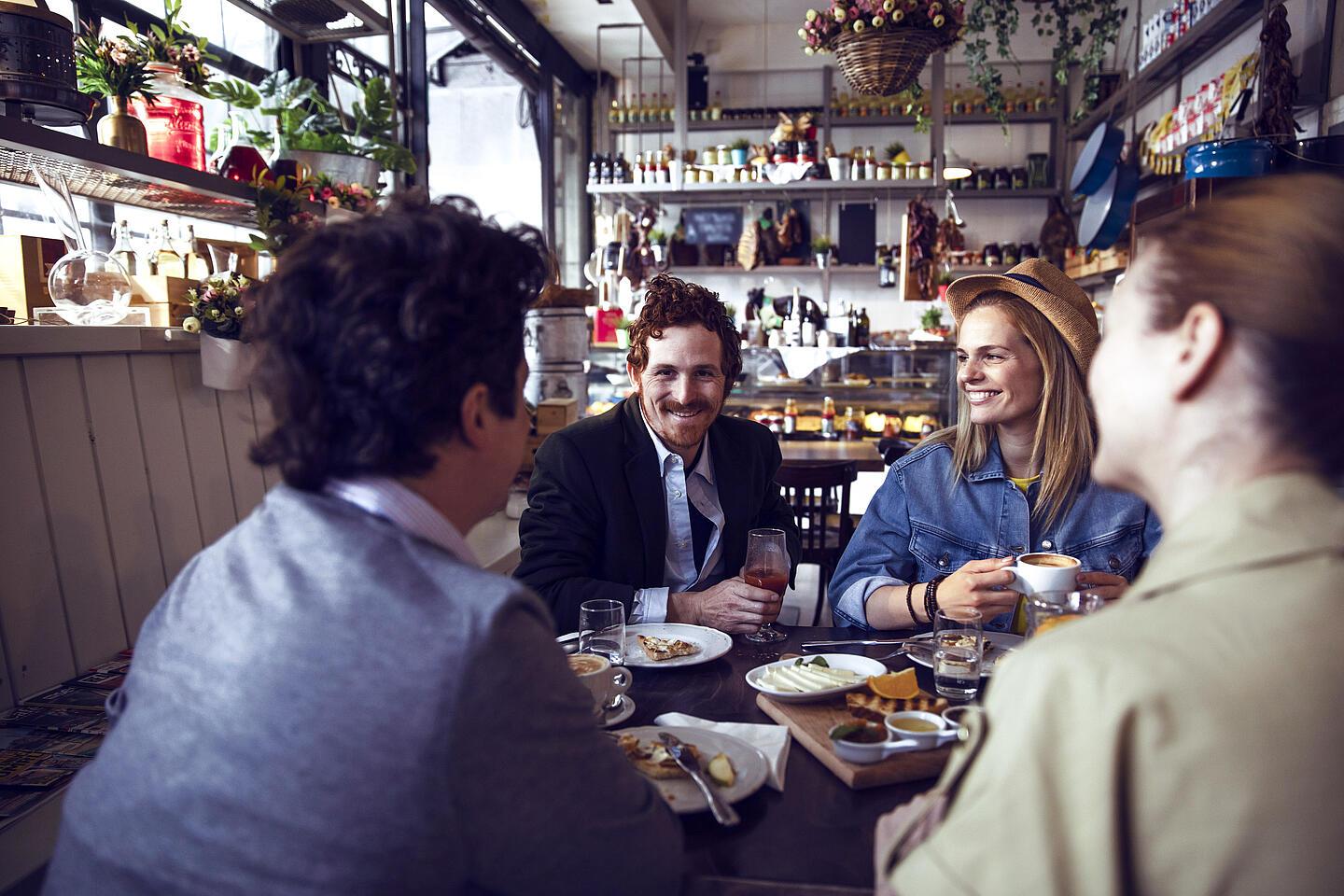 Vier Personen sitzen an einem Tisch im Restaurant und lachen