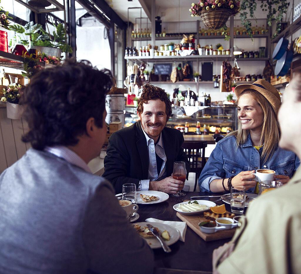 Vier Personen sitzen an einem Tisch im Restaurant und lachen