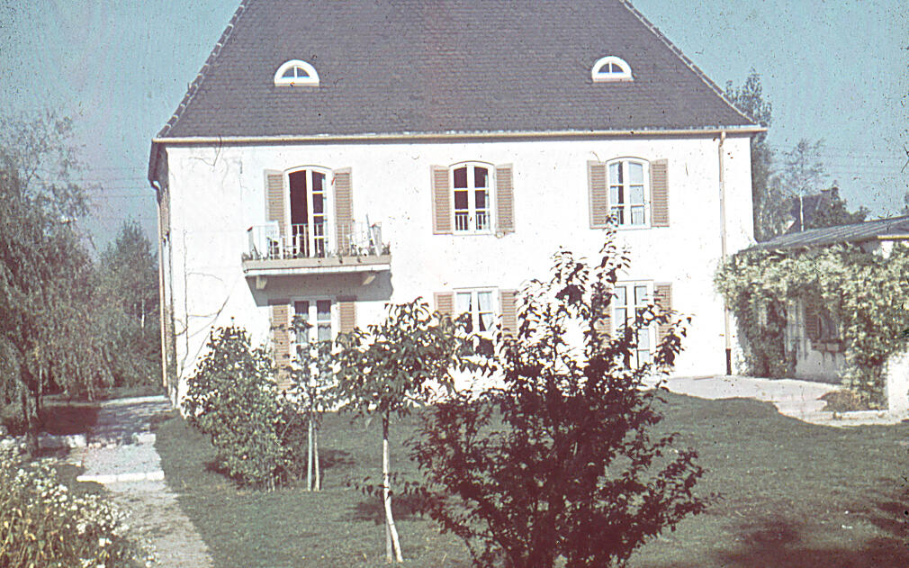 Man sieht ein weißes Haus mit einem Garten