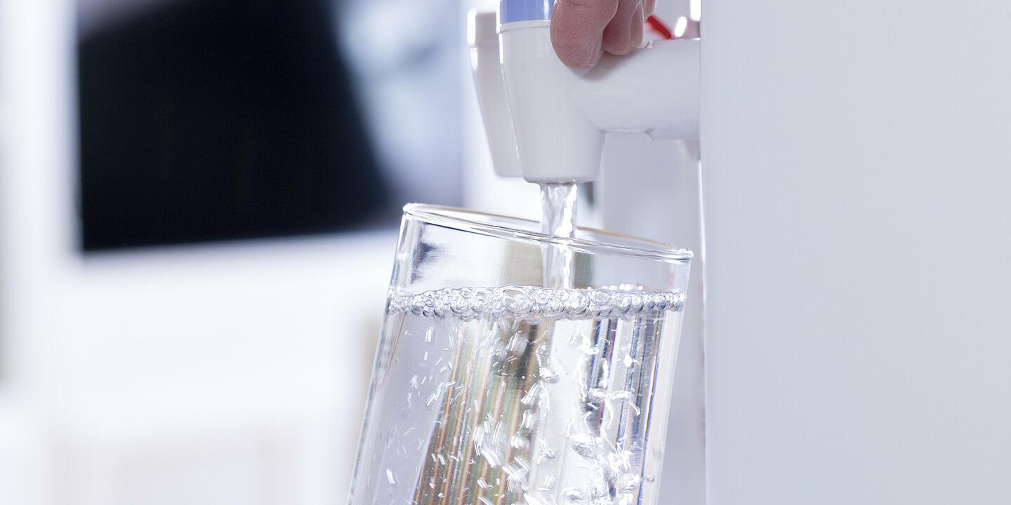 Ein Glas wird unter einer Schankanlage mit Wasser befüllt