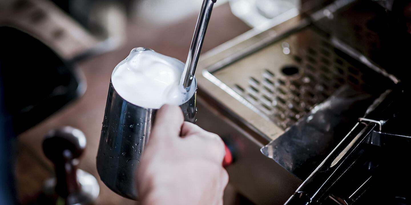 Es wird Milchschaum von einer Kaffeemaschine produziert