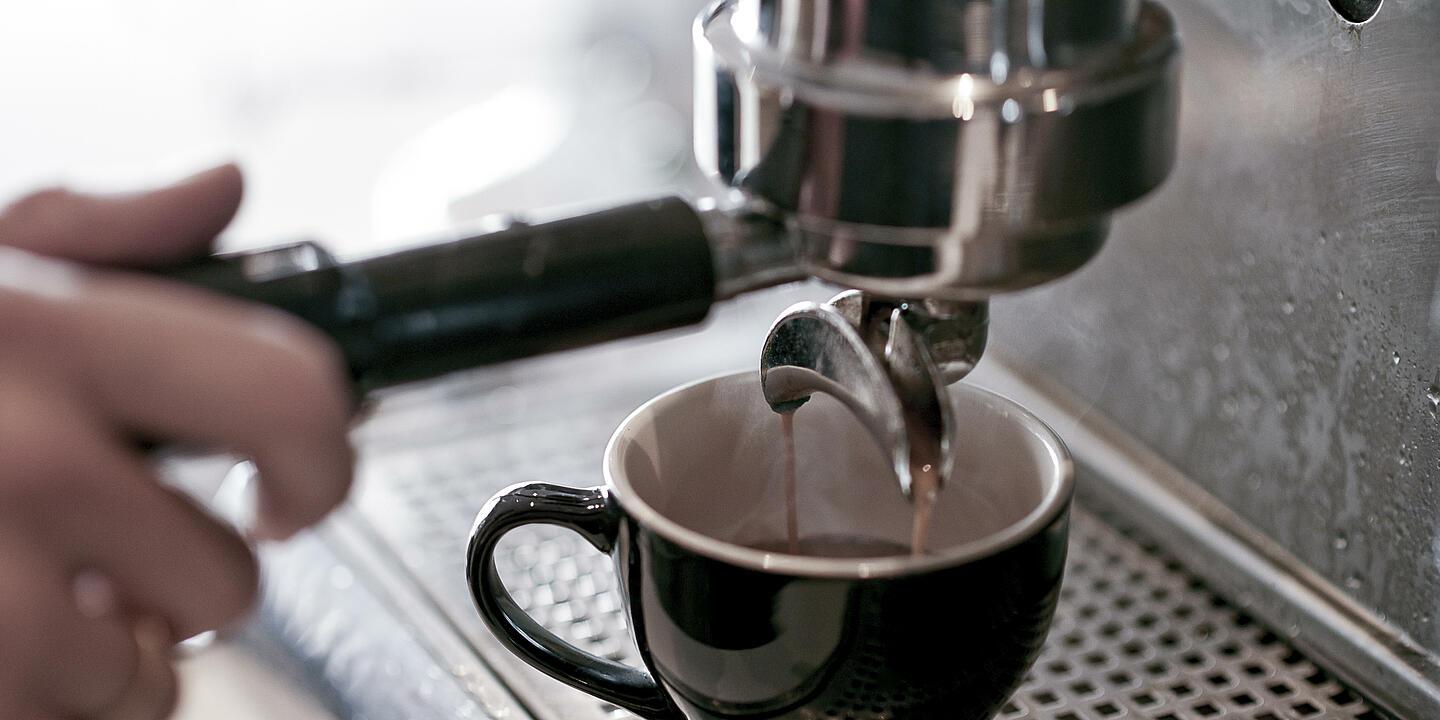 Eine Tasse wird von einer Kaffeemaschine befüllt